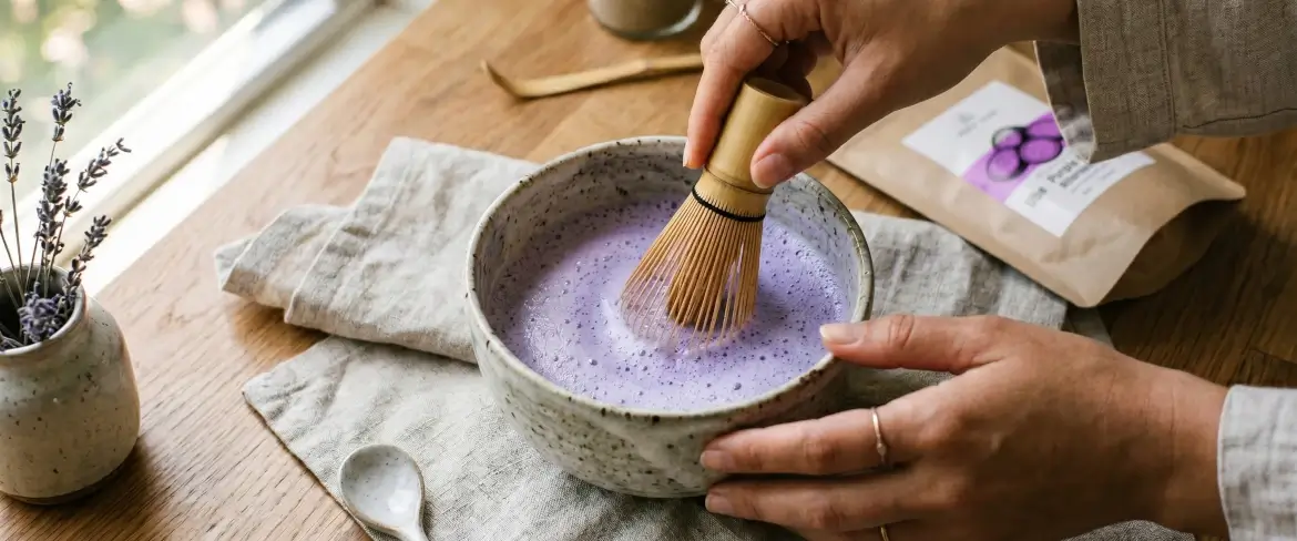 Tradycyjne przygotowanie purple matcha ube w miseczce przy użyciu bambusowej miotełki chasen